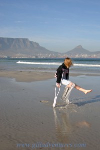A girl on crutches playing in the water on the beach north of Cape Town, South Africa